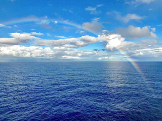 Full rainbow over blue ocean sea and sky after tropical rain during cruising Hawaiian Islands...
