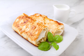 Tasty stuffed pancakes crepes with meat and sauce and basil. Food photography.