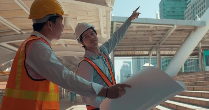 Engineering people are working in outdoor construction factory. Attractive Male foreman engineer are holding drawing working on construction side and leader are explaining about project.