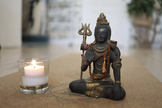 A Figurine Of God Shiva And A Candle Stand On A Cork Yoga Mat