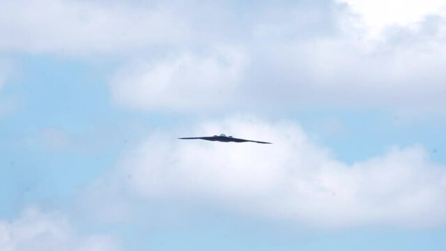 B2 Stealth Bomber jet airplane approach in cloudy sky, slow motion.