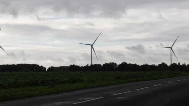 pair of turbines recorded from a highway, in a field in france