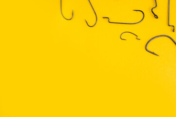 Fishing hooks on the trendy yellow backdrop. Flat lay, copy space. Fishing concept with worm hook.
