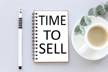 time to sell. text on white notepad paper. near cups with coffee and plants on a gray background.