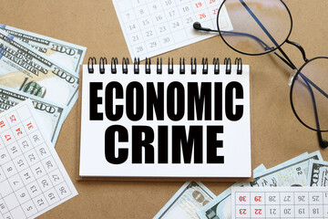 ECONOMIC CRIME. text on white notepad paper near calendar on wood craft background