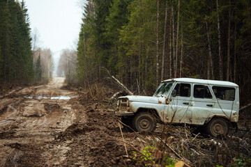 Obraz na płótnie Canvas a four-wheel drive all-terrain vehicle drives through the forest through the mud. a passable SUV with large wheels and high clearance. special transport for foresters rides through swamps and mud