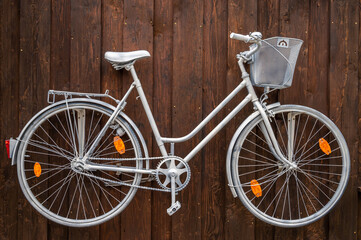 Fototapeta na wymiar Kreative Wandgestaltung mit einem alten weiß lackierten Fahrrad an einer Holzwand