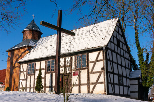 Half-timbered church Saint Matthew the Apostle dates from 1737 (kości&oacute;ł świętego Mateusza Apostoła). Wooden cross in front of the temple, the roof is covered with snow. Gardno (village), Poland.
