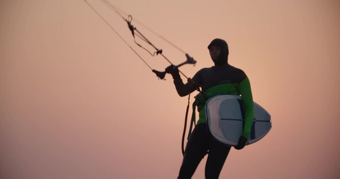 kitesurfer silhouette walking on beach at sunset 4k