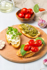 Fototapeta na wymiar Three bruschettas with tomatoes, ricotta and pesto on a round wooden tray. Close-up, vertical, selective focus.