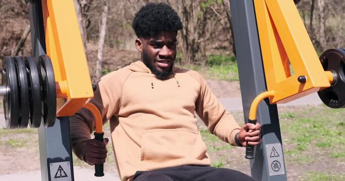African american man doing chest exercise on pec dec fly machine at park