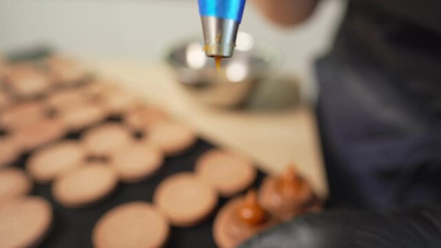 Process Of Making macaroon at home. Shot of hands of female pastry chef holding white macaron with ganache and squeezing red fruit jam from bag. Nature pastry macaroons. High quality 4k footage