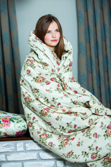 Fototapeta premium Young beautiful white woman awaking in light room. Relaxed woman lying in bed and drink tea. Good morning concept. Russian girl.