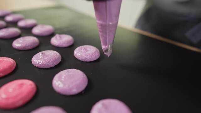 Process Of Making macaroon at home. Shot of hands of female pastry chef holding white macaron with ganache and squeezing red fruit jam from bag. Nature pastry macaroons. High quality 4k footage