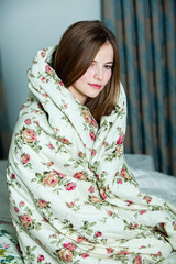 Fototapeta premium Young beautiful white woman awaking in light room. Relaxed woman lying in bed and drink tea. Good morning concept. Russian girl.