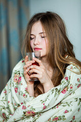 Young beautiful white woman awaking in light room. Relaxed woman lying in bed and drink tea. Good morning concept. Russian girl.