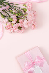 Mother's day background. Top view of gift with carnation bouquet on pink table background