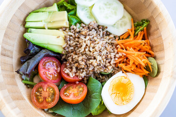 Brown rice salad with carrot, egg, cucumber, avocado, tomato and lamb's lettuce