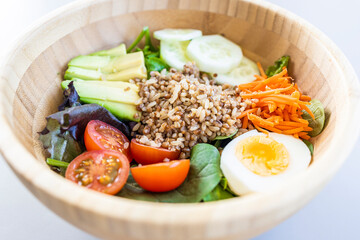 Brown rice salad with carrot, egg, cucumber, avocado, tomato and lamb's lettuce