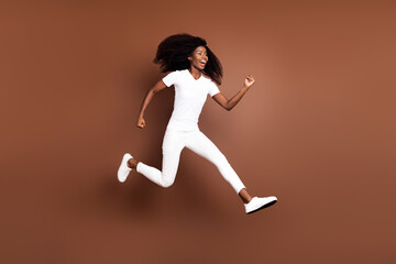 Fototapeta na wymiar Full length body size view of attractive cheerful motivated girl jumping running isolated over brown color background