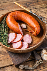 Sliced cold Smoked sausage in a wooden plate with thyme. wooden background. Top view