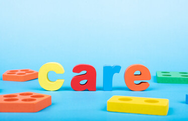 Care word written with wooden alphabets blocks on blue chart kids children background