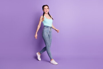 Fototapeta na wymiar Full body profile photo of funky brown hair lady go wear blue top jeans isolated on purple color background