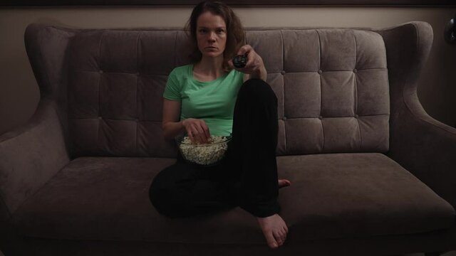 switch channel to tv using driver. woman with a bowl of popcorn
