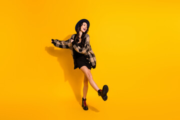 Plakat Photo of funny excited young lady dance wear black hat checkered coat isolated yellow color background