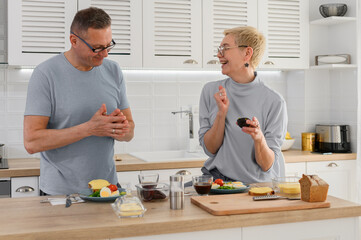 Smiling senior couple cooking healthy food with healthy fresh vegetables on kitchen 