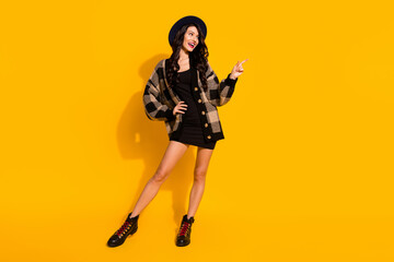 Photo of lady direct finger up look empty space wear hat plaid coat short dress boots isolated yellow color background