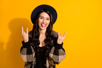 Photo of funky hipster lady show horns tongue out wear black hat plaid jacket isolated yellow color background