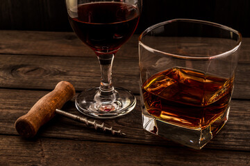 Glass of brandy and red wine with corkscrew on an old wooden table. Angle view