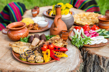 Fototapeta na wymiar Homemade Romanian Food with grilled meat, polenta and vegetables Platter on camping. Romantic traditional Moldavian food outside on the wood table.