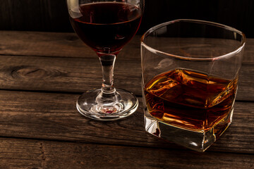 Glass of brandy and red wine on an old wooden table. Angle view