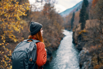 woman hiker with backpack on her back near mountain river in nature