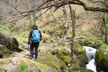 Woman crossing a river, with backpack. Lifestyle and nature concept