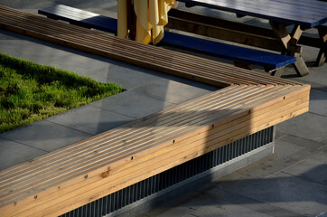 square table with shrub and lawn in the middle. around are wooden benches and paneling planks....