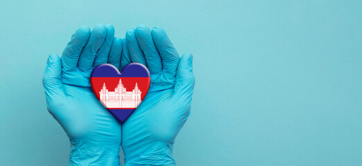 Doctors hands wearing surgical gloves holding Cambodia flag heart