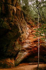 Beautiful red sandstone cliffs and cave of the Licu Langu sandstone massive near Gauja river in Latvia