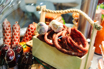 Smoked sausage in a wooden box in a shop window. Trade in meat delicacies in the retail network. Close-up