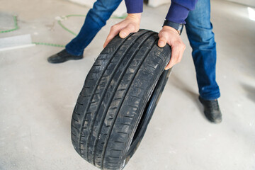 Damaged car tire in the hands of a car mechanic. Replacing rubber for safe road travel. Foreground....