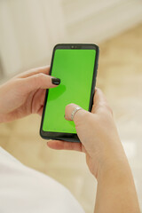 Girl holding a phone with a green screen in her hands and typing a message on it