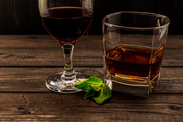 Glass of brandy and red wine with mint sprig on an old wooden table. Close up view