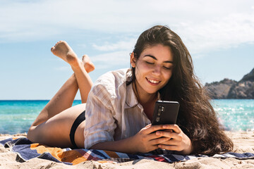 young woman using her mobile in the beach