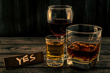Three glasses with brandy, tequila and red wine with the wooden plank on it is an inscription 