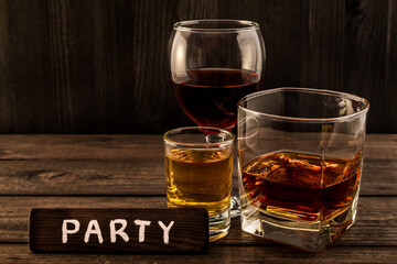 Three glasses with brandy, tequila and red wine with the wooden plank on it is an inscription 