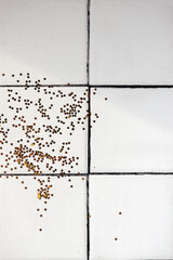 Spilled golden glitter sequins on white tile floor or countertop background. Copy space. Top view.