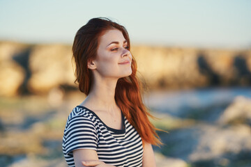 Fototapeta premium woman travels in the mountains in nature near the river and striped t-shirt