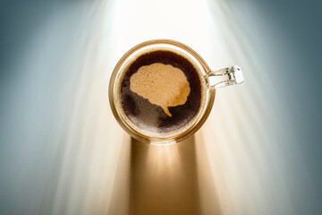 coffee cup with brain icon, top view on background with sunlight.